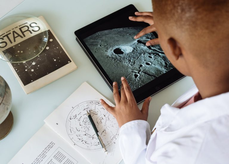 Crop African American student studying craters of moon on tablet at observatory